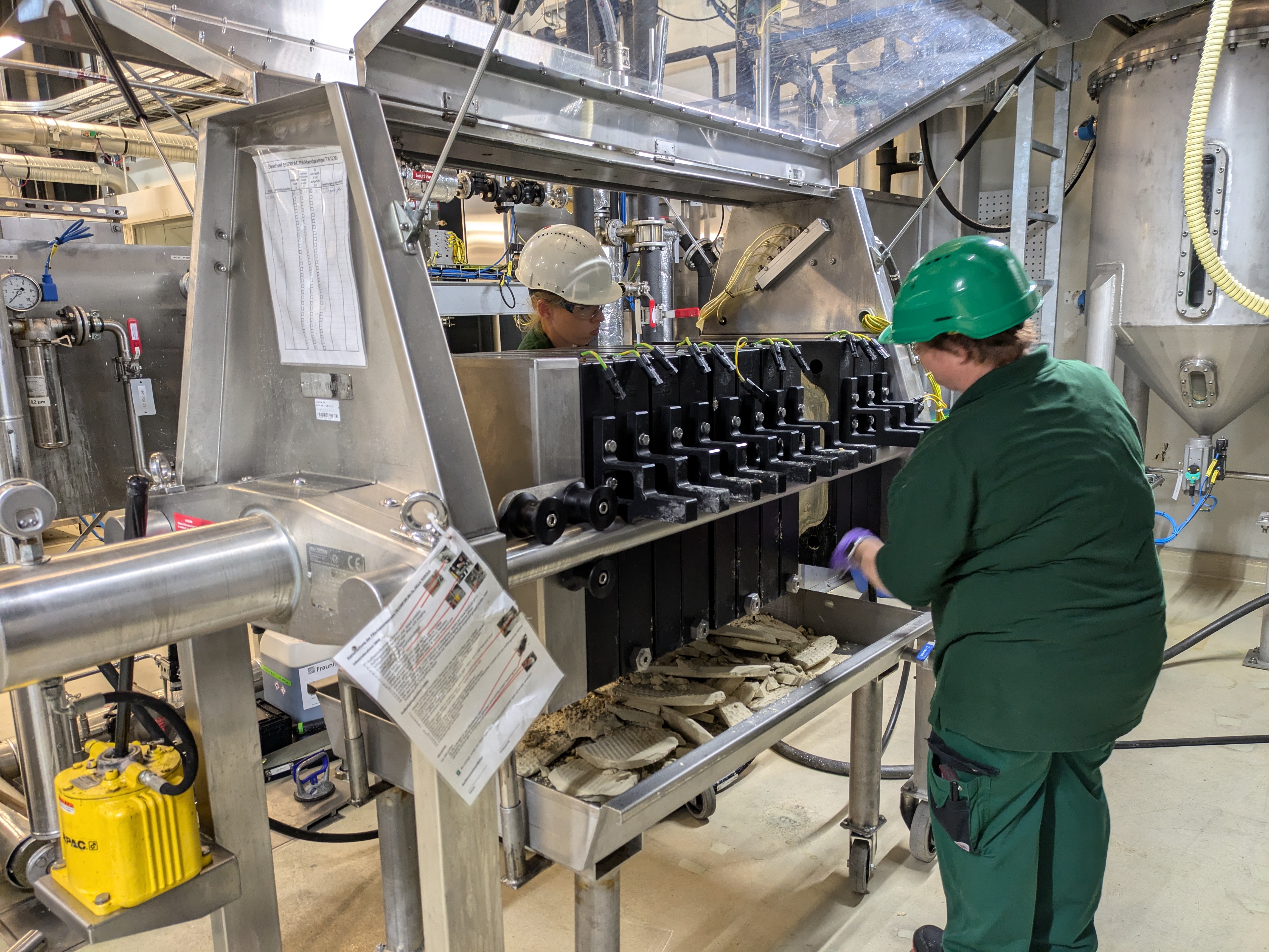 Mitarbeiter stehen an der Filterpresse, mit der Rapskerne entölt werden