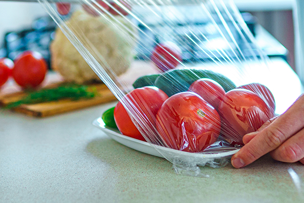 Verpackungsfolie über Schale mit Tomaten und Gurken