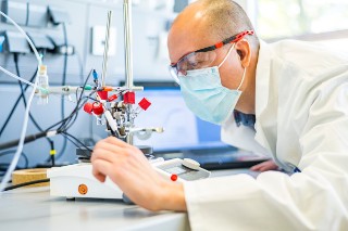 Projekt »eBioCO2n« Wissenschaftler stellt etwas an einer auf einem Tisch stehenden Apparatur ein.